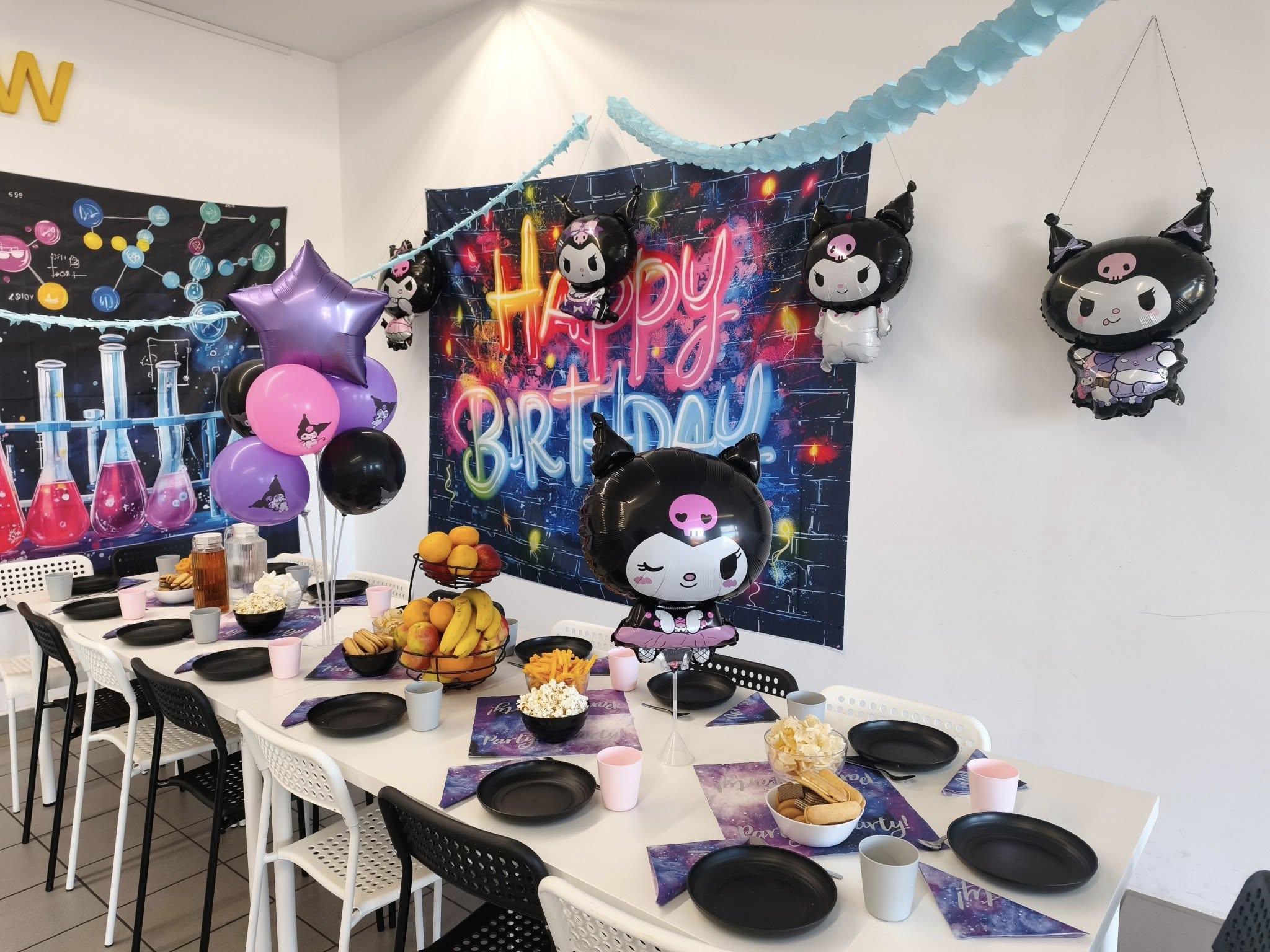 Kolorowa dekoracja urodzinowa z balonami w stylu bohaterów kawaii, na świątecznym stole z przekąskami, napojami i owocami, z napisem "Happy Birthday" na tle graffiti, idealne do organizacji przyjęcia dla dzieci.