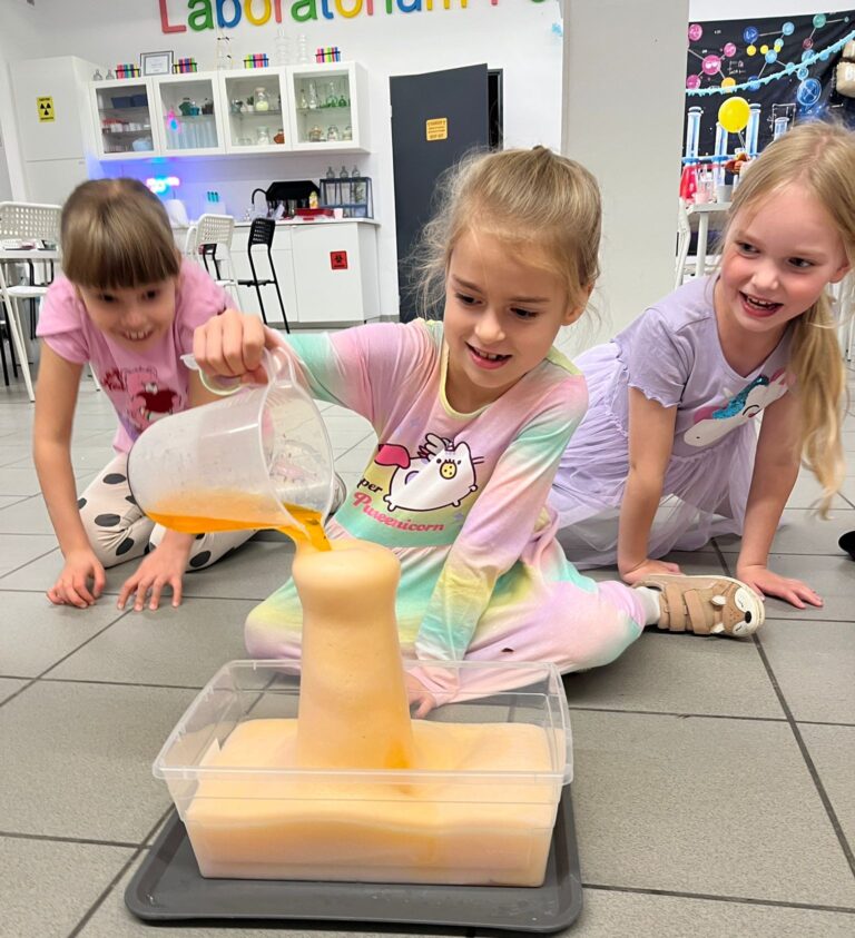 Kolorowe dzieci bawią się w laboratorium, przelewając ciecz do formy wtniającej. Eksperyment chemiczny dla dzieci w nowoczesnym centrum nauki, rozwijający kreatywność i wiedzę o naukach przyrodniczych.